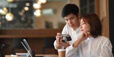 Bilgisayarlı dizüstü bilgisayar ve belgeyle çalışan genç bir çiftin fotoğrafı. Ahşap masada otururken rahat bir kafe üzerinde arka plan olarak çalışıyor..