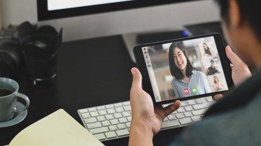Akıllı adamın konuştuğu, açıkladığı ve meslektaşı ile video görüşmesi yaparken bilgisayar monitörünün önünde oturduğu fotoğraf. Video konferans konseptiyle evden çalışmak.