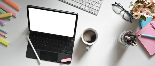 Top view white workspace is surrounding by a white blank screen computer tablet and various equipment.