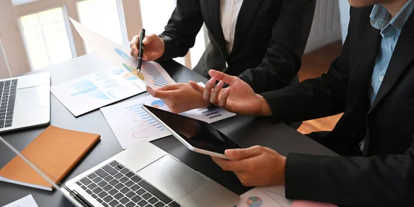 Cropped image of business development team meeting/talking about their new business project result while sitting together at meeting table over comfortable office as background.