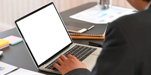 Cropped image of business executive men discussing about their business plan with computer laptop and graphic charts while sitting together at black meeting table over modern office as background.