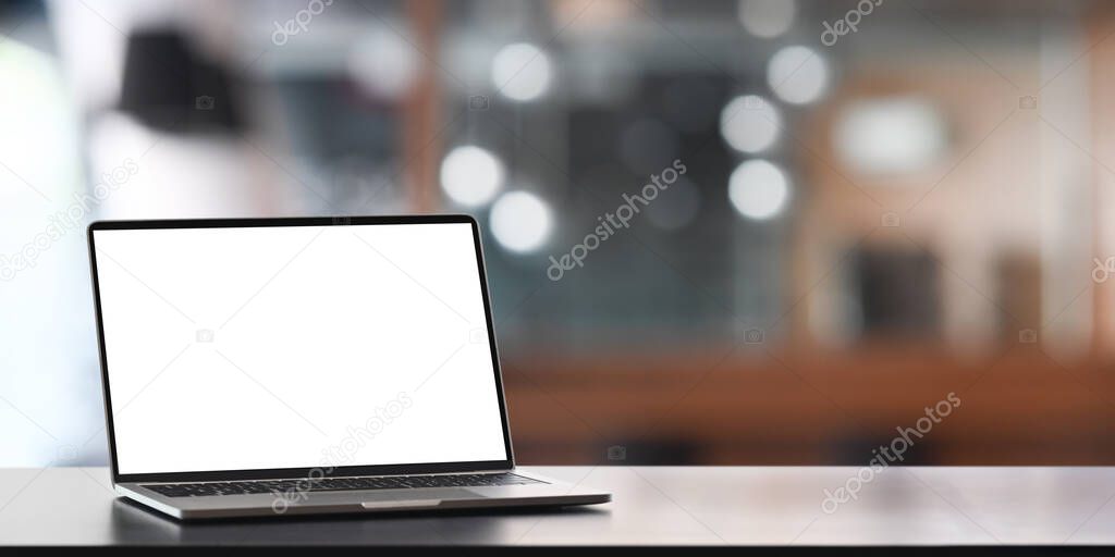 Computer laptop with white black screen putting on counter bar over blurred office as background.