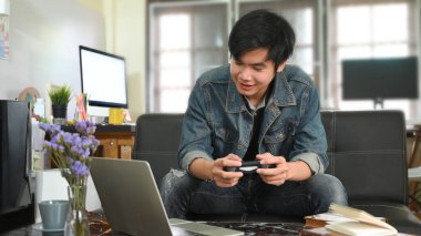 Akıllı bir adam video oyunu oynuyor ve önünde oturuyor.