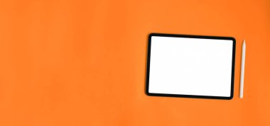 Boş ekranlı bilgisayar tableti ve turuncu arka planda stil kalemi.