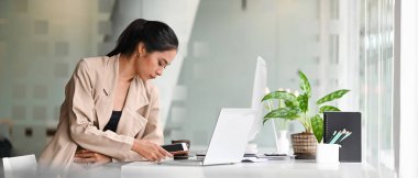 Yaratıcılık ofisinde cep telefonunu tutan çekici kadın tasarımcı..