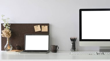 Masada ofis ekipmanlarıyla birlikte beyaz boş ekran dizüstü bilgisayar ve bilgisayar monitörü 