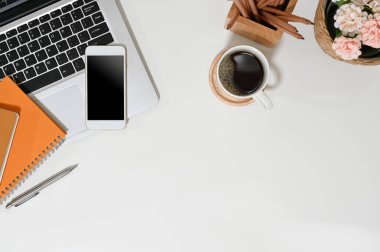 Üst görünüm çalışma alanı dizüstü bilgisayarı, cep telefonu, defter, kahve ve çiçek.