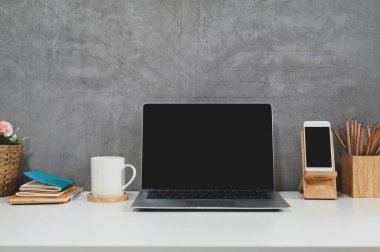 Laptop, akıllı telefon, kahve ve beton duvarlı ofis malzemeleri olan çatı katı çalışma alanı..