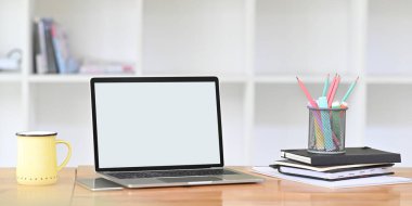 Ofis ekipmanları ve kupalarla çevrili ahşap çalışma masasında boş ekran bilgisayar laptopu