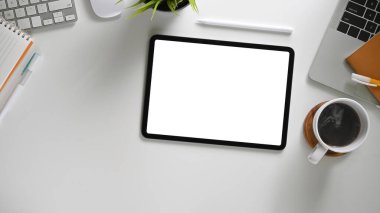 Çalışma alanı üzerinde beyaz boş ekranı olan dijital tabletin üst görünümü 