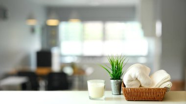 Mum, saksı, sepet ve beyaz masa üzerinde havlular. 