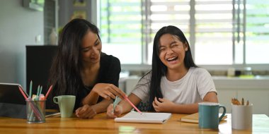 Bir anne kızıyla oturuyor ve tahtadan çalışma masasında ödevini yapıyor..
