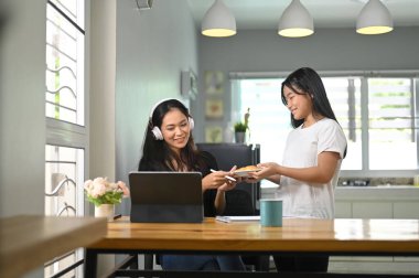 Annesi tablet bilgisayarda çalışırken küçük kız annesi için fırın hizmeti veriyor..
