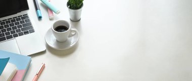 Kahve fincanı, laptop ve diğer ofis ekipmanları beyaz çalışma masasında. 