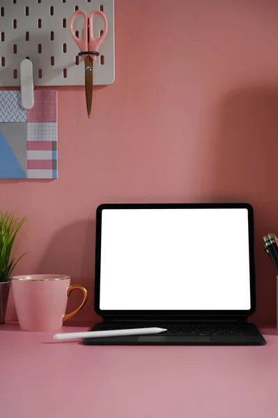 Computer tablet with a white blank screen is putting on a woman workspace.