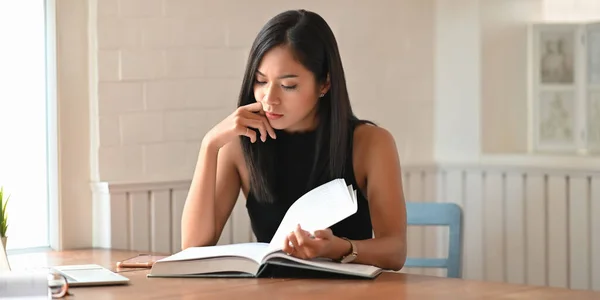 Bir Üniversite Öğrencisi Ahşap Çalışma Masasında Otururken Kitap Okuyor — Stok fotoğraf