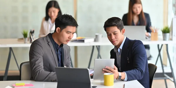 사업가들은 사무직 근로자들을 배경으로 책상에 컴퓨터 태블릿으로 일하고 — 스톡 사진