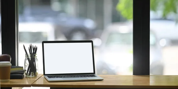 blank screen laptop on counter bar surrounded by pencil holder and equipment