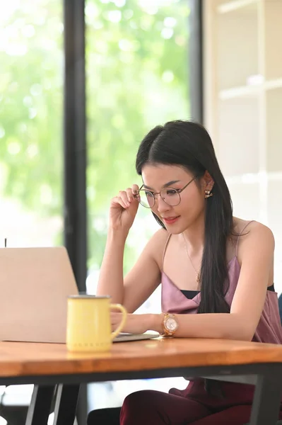 Uma Mulher Com Óculos Está Usando Laptop Computador Enquanto Está — Fotografia de Stock