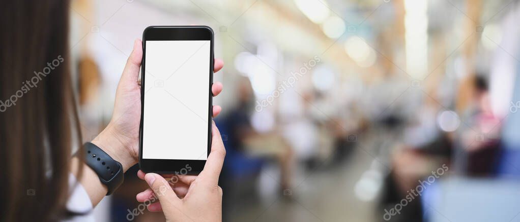 Cropped image of hands is using a white blank screen smartphone in public train.