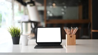 Boş ekranlı tablet bilgisayar ve modern ofisteki beyaz ofis masasında kahve..