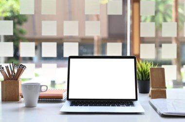 Boş ekranlı dizüstü bilgisayar ve çalışma masasında ofis malzemeleri..