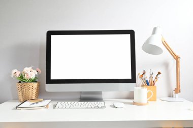 Bilgisayarın görüntüsünü beyaz ekran, kahve fincanı, bitki, lamba ve ofis malzemelerini minimal çalışma masasına yerleştir.