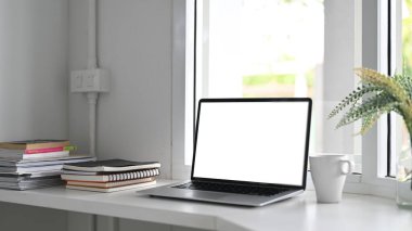 Kitap, dergi ve kahve fincanı olan beyaz masadaki dizüstü bilgisayar..