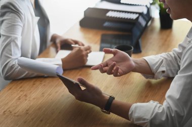 Başlangıç ekibinin toplantı odasında akıllı telefon kullanırken fikir alışverişinde bulunması..