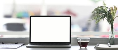 Minimum çalışma alanına beyaz sceen kahve fincanı, belge ve bitki içeren dizüstü bilgisayar.