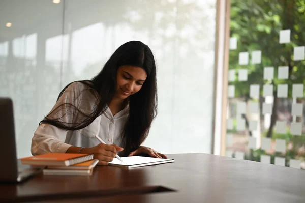 Female graphic designer using stylus pen drawing on blank screen tablet in modern office.