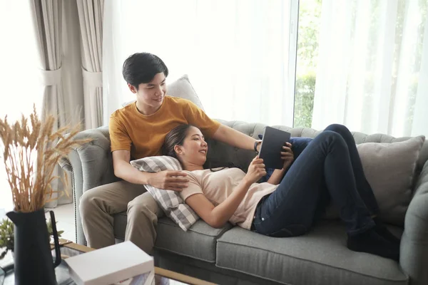 幸せな若いカップルはリビングルームで一緒に楽しみを持ってデジタルタブレットでオンラインメディアを見て — ストック写真