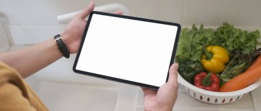 Cropped shot of man hands holding tablet with empty screen in the kitchen.