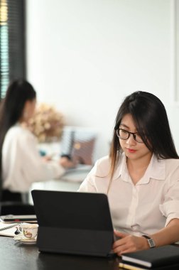 Modern ofiste bilgisayar tableti üzerinde çalışan serbest çalışan genç bir kadın.. 