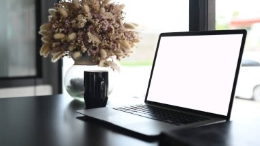 Comfortable workplace with white screen laptop, coffee cup and potted plant.For graphic display montage.