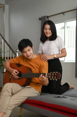 Erkek arkadaşı oturma odasında güzel kız arkadaşına gitar çalıyor..