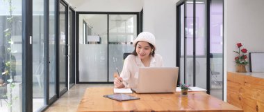 Çevrimiçi dizüstü bilgisayarda çalışan ve ev ofisinde yeni bir proje yapan genç bir kadın serbest yazar..