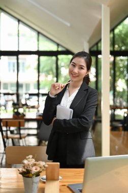 Gülümseyen zeki ve çekici genç bir kadının portresi lobide dikilip kameraya bakıyor..