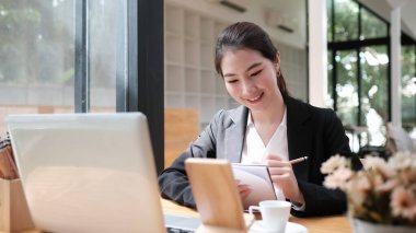 Çalışanların çalışma programı üzerinde düşünen kadın yöneticinin portresi dizüstü bilgisayar kullanırken not defterine rapor yaz.