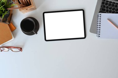 Designer workspace tablet with white screen, note book, office supplies and coffee cup for graphics display montage.