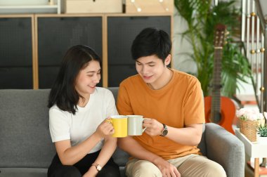 Neşeli, genç ve güzel bir çift sabahları kanepede birlikte kahve içiyor..