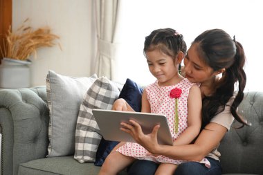 Anne ve kızı oturma odasındaki kanepede televizyon izliyorlar..