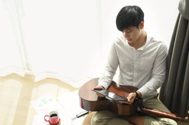 Modern evdeki şarkı sözleri için tabletle yerde oturan genç adamın portresi..