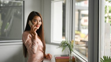 Modern ofiste cep telefonuyla konuşan çekici genç bir bayan..