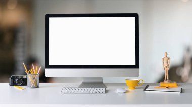 Mock up blank screen computer  and camera with designer supplies on white desk.