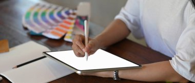 Cropped shot of graphic designer working with graphic drawing tablet and colour palette in photo studio.