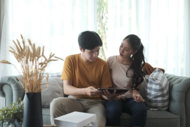 Sevgi dolu çift rahat koltukta dijital tablet ekrana bakıyor..