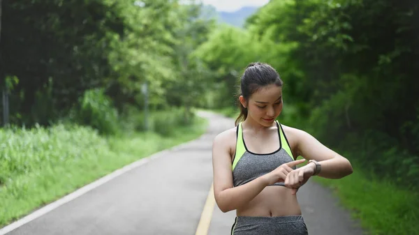 Νεαρή Γυναίκα Ρύθμιση Smartwatch Πριν Από Τρέξιμο Στο Πάρκο — Φωτογραφία Αρχείου