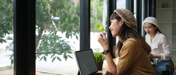 Side view of woman take a break with coffee cup while online working in meeting room.