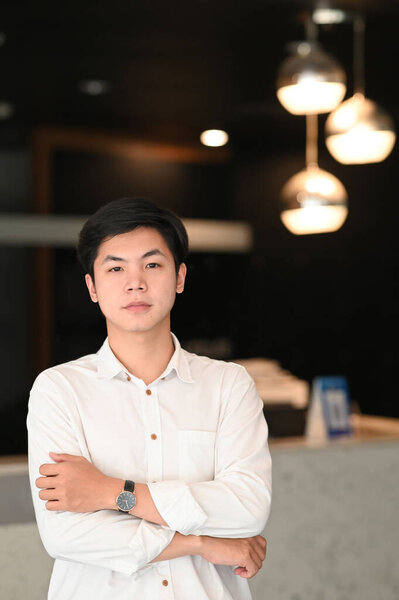 Портрет мужчины-предпринимателя со скрещенными руками, уверенного в креативном кабинете.